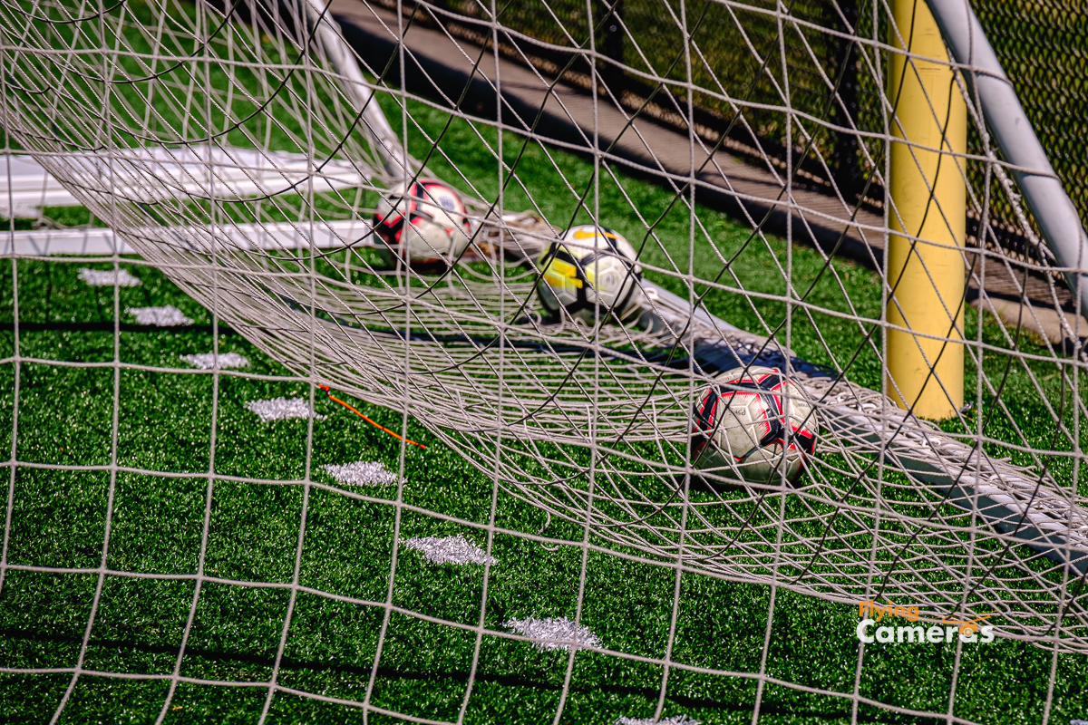 Soccer balls at the base of a soceer net