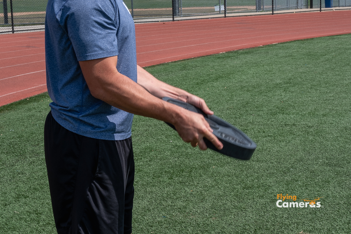 Youth exercises with 45 lb plate at an athletic field