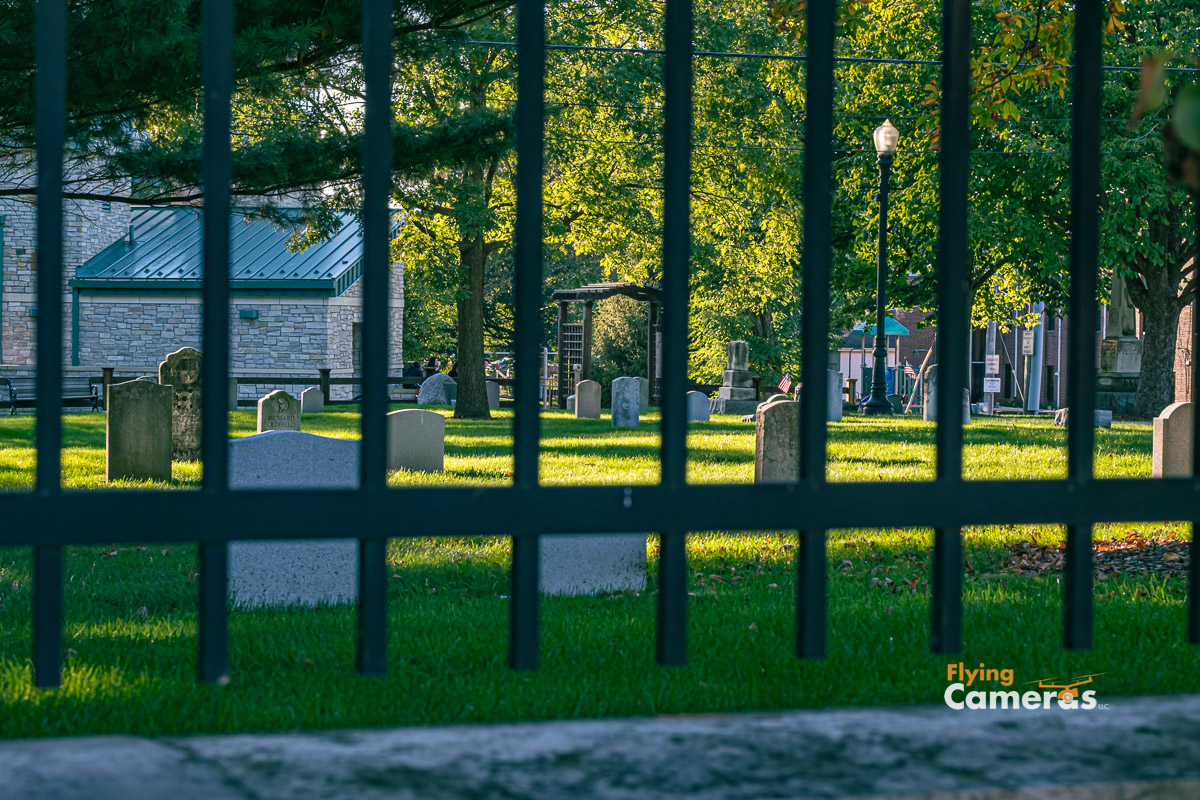 View of Downers Grove cemetery through a wrought iron fence on a summer day
