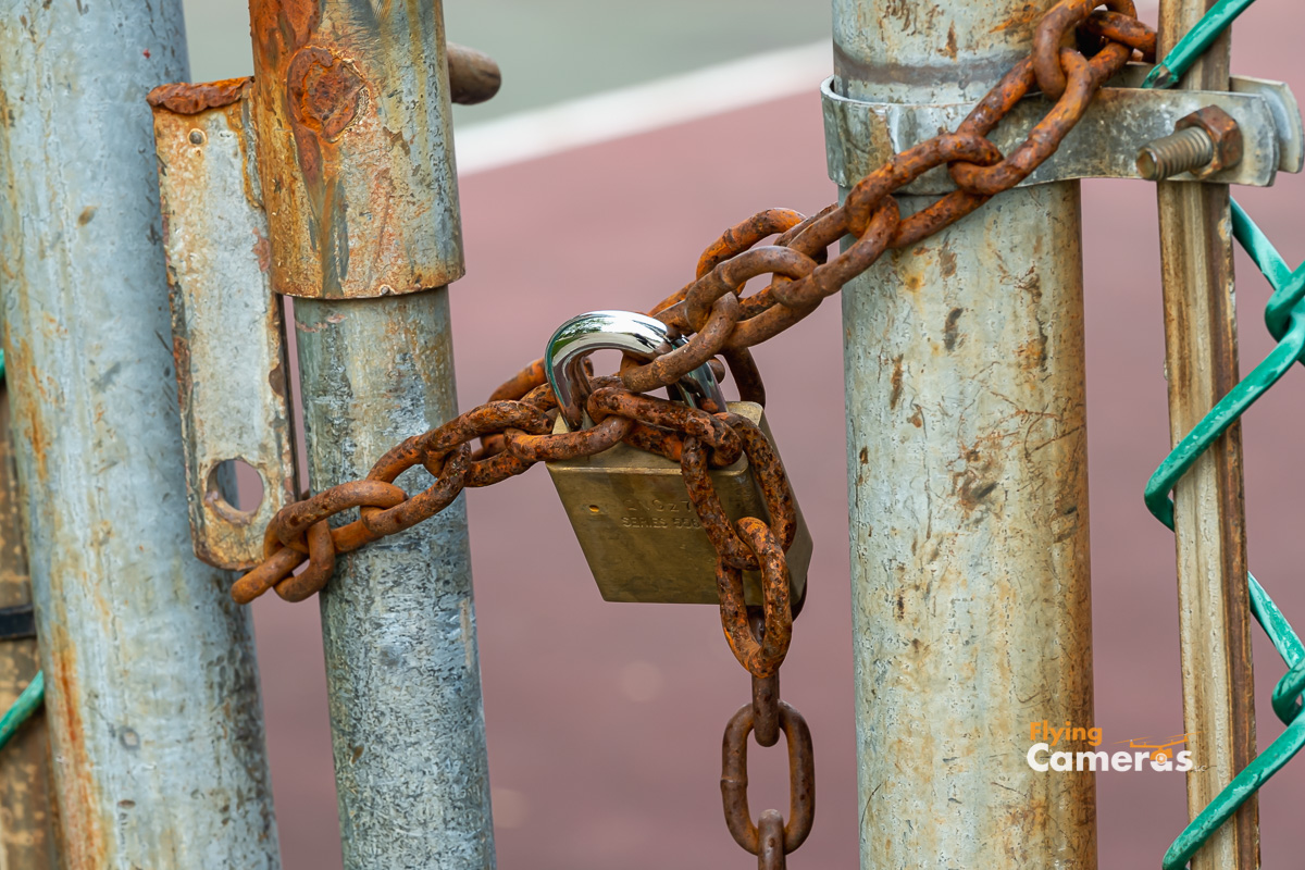 Padlock on rusty chain at tennis courts