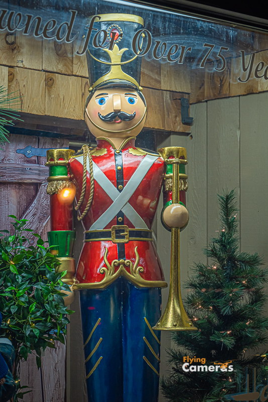 Dapper toy soldier w/mustache and colorful uniform holding a trumpet set in a holiday christmas scene
