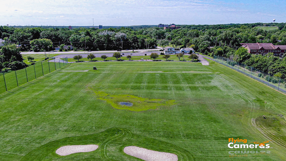 Image of a golf driving range with lush green grass taken at 225 ft from a drone